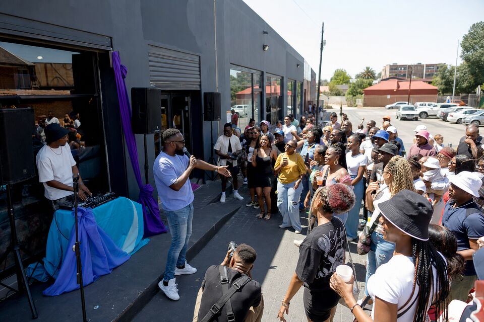 A presenter with a microphone engaging a lively street crowd at a small business activation