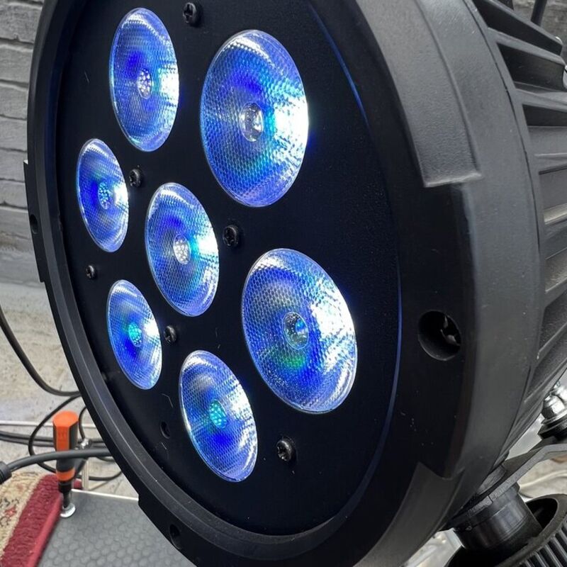 Close-up of an LED stage light glowing blue on a lighting truss
