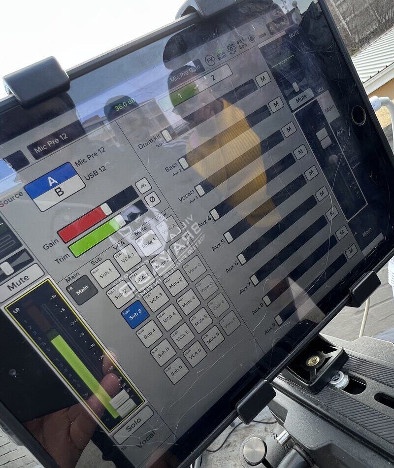 A tablet running a live sound mixing app with channel faders and meters